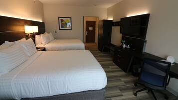 A hotel room with two beds, a desk, a chair, a TV, and a painting on the wall.