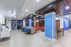 A modern dining area with high tables and chairs, a counter with a beverage station, and a meeting room indicated by a sign. - Holiday Inn Express & Suites Coffeyville by IHG (Coffeyville)