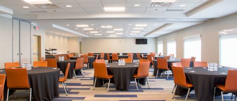 A conference room with multiple tables and chairs, equipped with water bottles, and a carpeted floor.