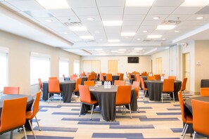 Une salle de conférence dotée de plusieurs tables et chaises, disposées en rangées.