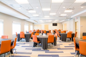 Un salón de conferencias con varias mesas y sillas, dispuestas en filas.
