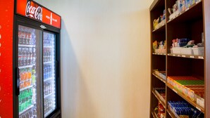 A vending machine with a Coca-Cola sign and a shelf stocked with various products. - Holiday Inn Express & Suites Danville by IHG (Danville)