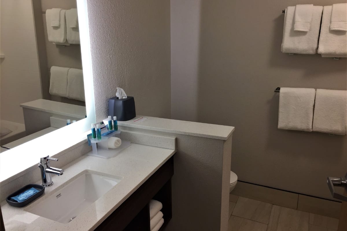 A bathroom with a white sink, mirror, and towel rack.
