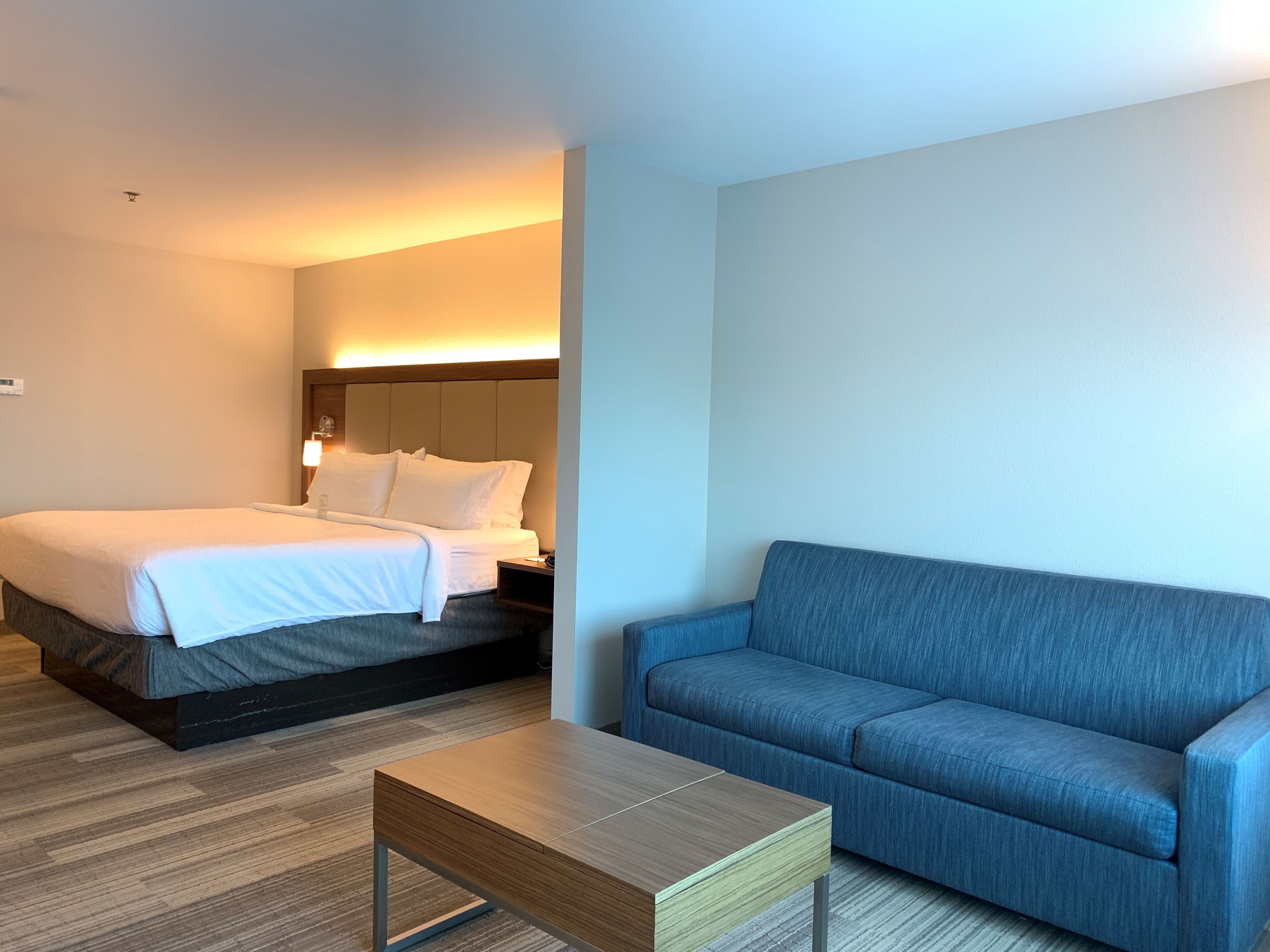 A hotel room with a bed, a sofa, and a small table.