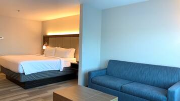 A hotel room with a bed, a sofa, and a small table.