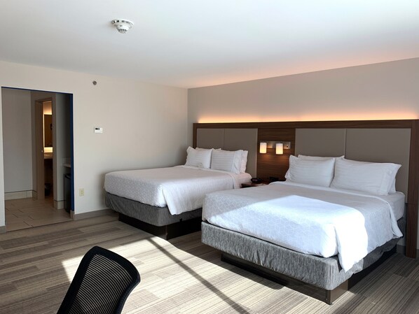 Une chambre d’hôtel avec deux lits, une tête de lit en bois, une table de chevet et une chaise.