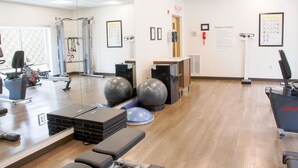 A fitness center with exercise equipment, a reception area, and informational posters on the walls. - Holiday Inn Express & Suites Danville by IHG (Danville)