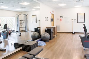 Un gimnasio con equipo de ejercicio, una zona de recepción y carteles informativos en las paredes.