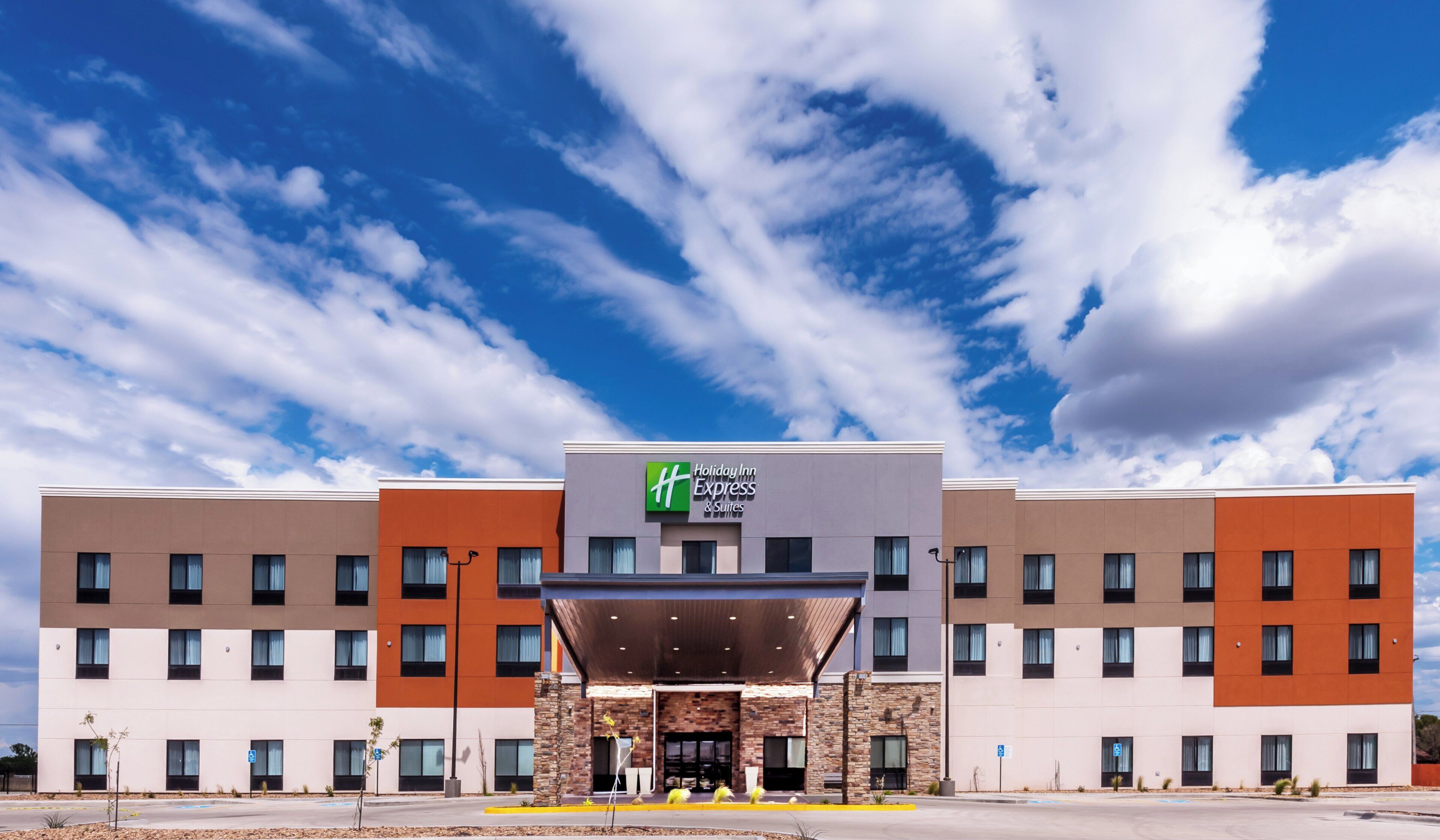 A Holiday Inn Express hotel with a modern facade, multiple floors, and a clear sky.