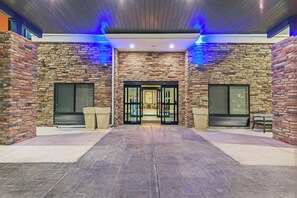 A building entrance with a stone facade, a glass door, and a bench. - Holiday Inn Express & Suites Perryton by IHG (Perryton)