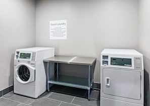 A guest laundry area with two washing machines and a table, a sign with laundry instructions, and a tiled floor. - Holiday Inn Express & Suites Perryton by IHG (Perryton)