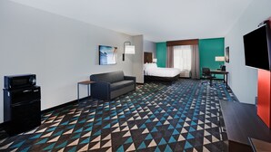 A hotel room with a bed, a sofa, a desk, a TV, and a microwave. - Holiday Inn Express & Suites Perryton by IHG (Perryton)