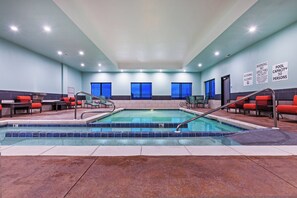 A hotel pool area with a 30-person capacity sign, a lifeguard duty sign, and a no diving allowed sign.