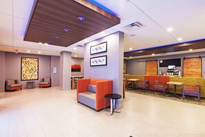 A modern lobby with seating areas, a reception desk, and a wall with framed artwork.