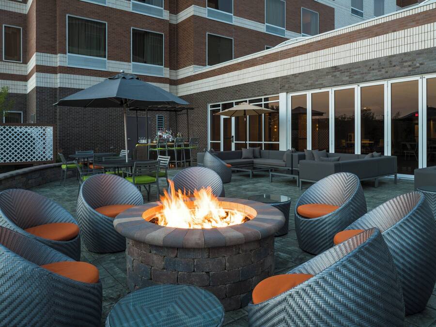 Un patio al aire libre con una chimenea, muebles de mimbre y un muro de ladrillo.