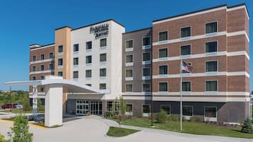 A Fairfield Inn & Suites by Marriott hotel with a modern brick facade, a covered entrance, and a flagpole with an American flag.