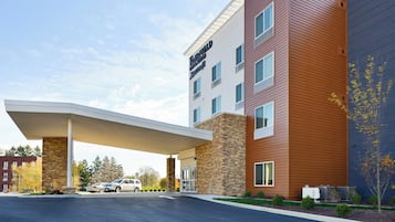 A hotel with a modern design, featuring a covered entrance, multiple floors, and a parking area.