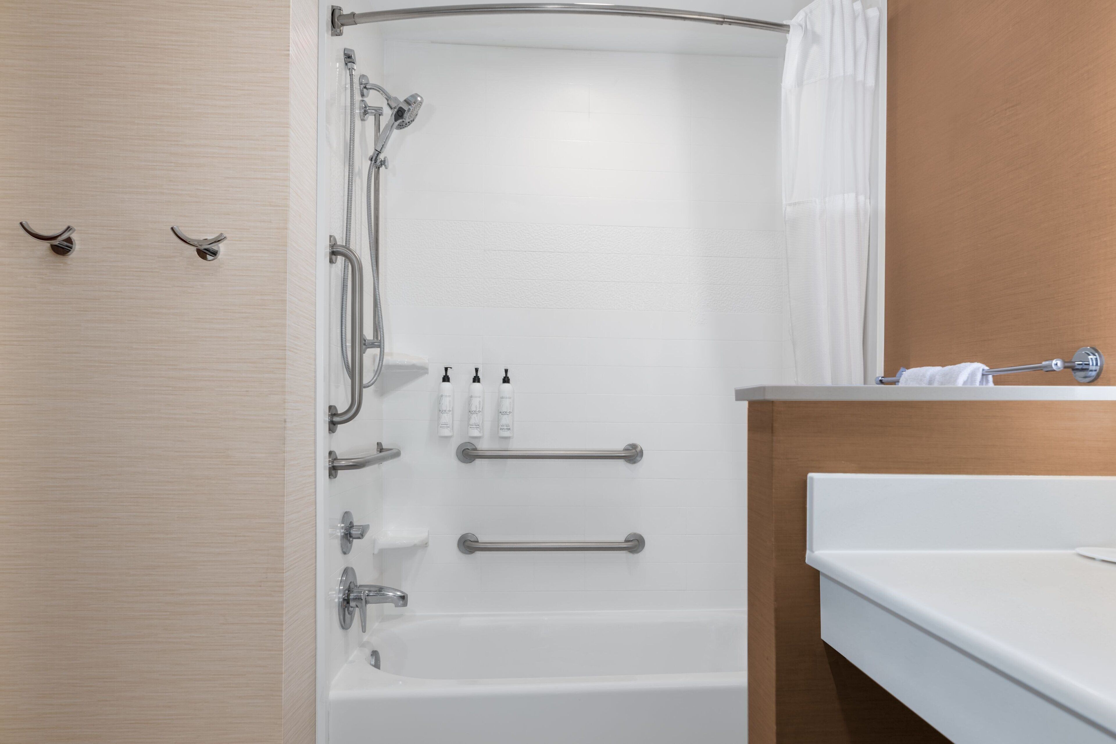 Une salle de bain moderne avec une baignoire blanche, une douche dotée d’une porte en verre et un meuble-lavabo en bois avec un miroir.