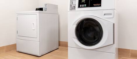 Twee witte commerciële wasmachines in een ruimte met houten vloer en witte wanden.
