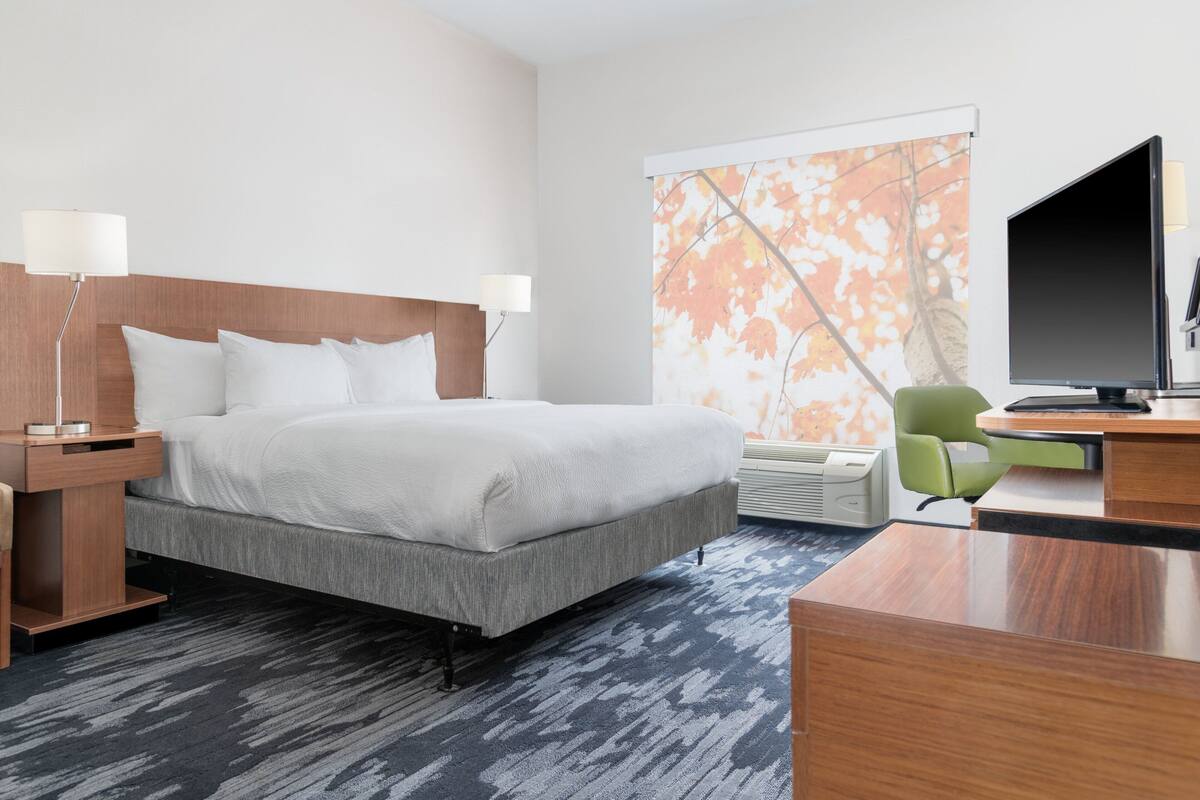 Une chambre d’hôtel équipée d’un lit, d’un bureau, d’une chaise et d’un téléviseur.