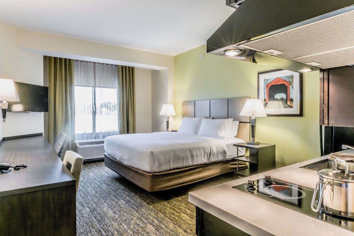 Une chambre d’hôtel avec un lit, un bureau et une kitchenette.