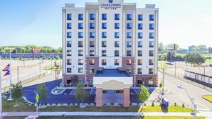 A multi-story hotel with a prominent 'Candlewood Suites' sign, a parking lot, and a flagpole with the American flag. - Candlewood Suites Hartford Downtown by IHG (Hartford)