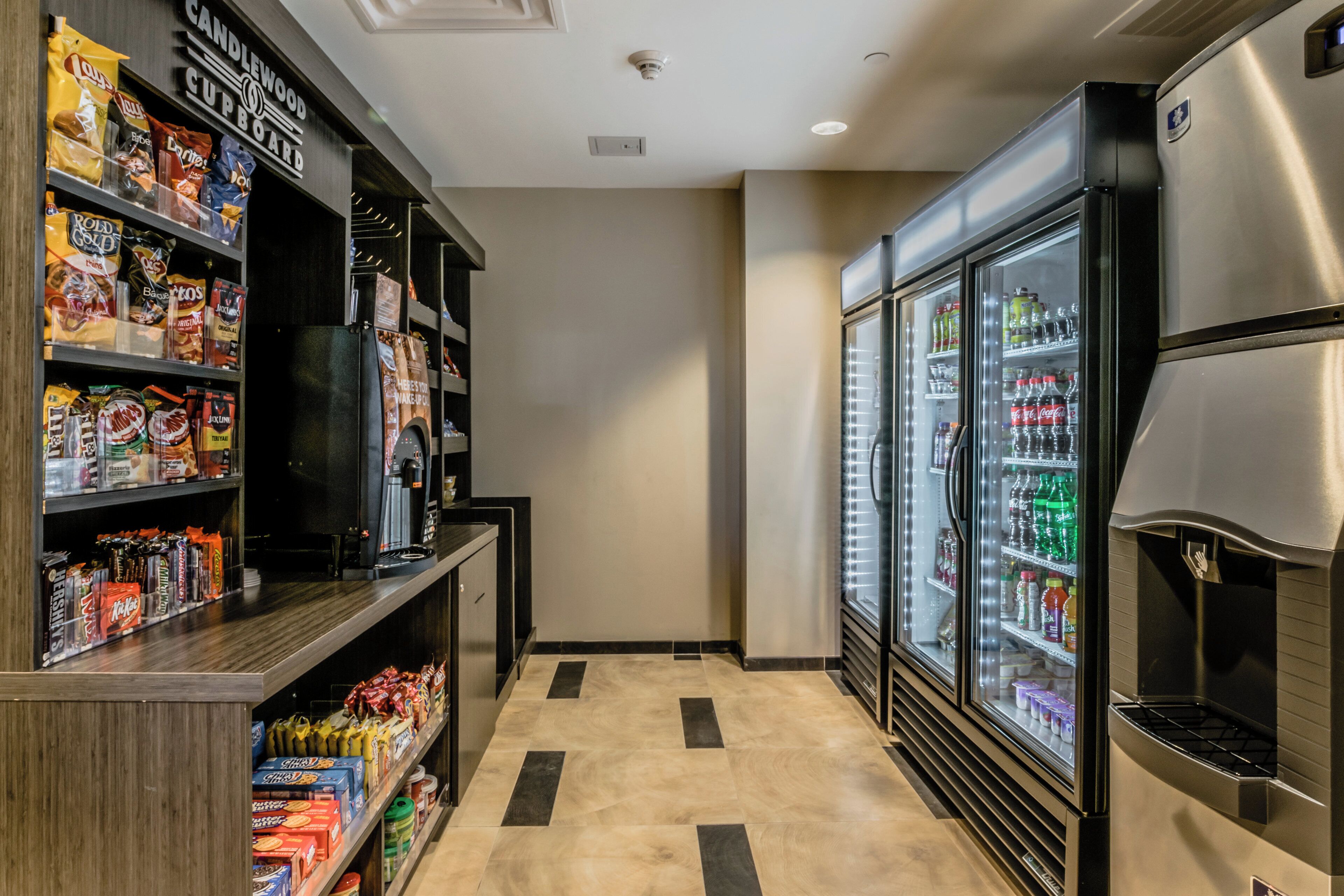 A narrow hallway with vending machines, snack shelves, and a refrigerator.