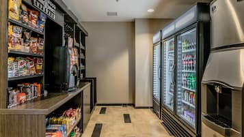 A narrow hallway with vending machines, snack shelves, and a refrigerator.