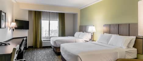 A hotel room with two beds, a desk, a chair, a TV, and a window with curtains.