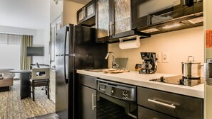 Cocina moderna con refrigerador, estufa y lavavajillas. Cuenta con un comedor con mesa y sillas.