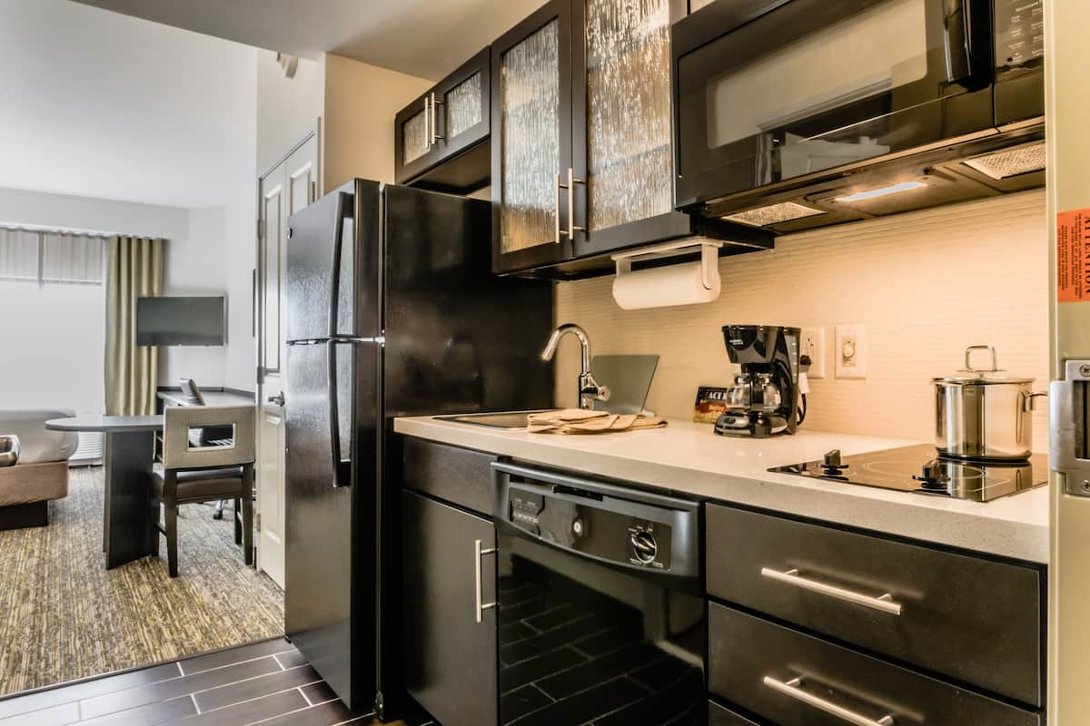 Cocina moderna con refrigerador, estufa y lavavajillas. Cuenta con un comedor con mesa y sillas.