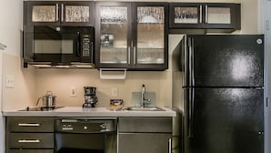Una cocina moderna con electrodomésticos de acero inoxidable, incluyendo un refrigerador, lavavajillas y microondas.