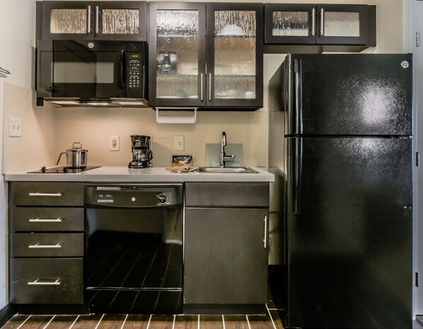 Una cocina moderna con electrodomésticos de acero inoxidable, incluyendo un refrigerador, lavavajillas y microondas.