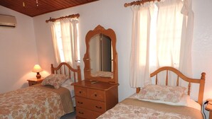 A bedroom with two beds, a dresser, a mirror, and a nightstand with a lamp. - Villa 230C at Jolly Harbour (Jolly Harbour)