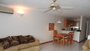 A living room with a beige sofa, a wooden coffee table, and a ceiling fan. - Villa 230C at Jolly Harbour (Jolly Harbour)