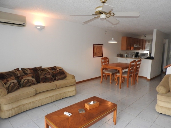 A living room with a beige sofa, a wooden coffee table, and a ceiling fan.