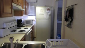 A compact kitchen with a stove, microwave, and refrigerator. There is a sink with a dish rack and a coffee maker. - Villa 230C at Jolly Harbour (Jolly Harbour)