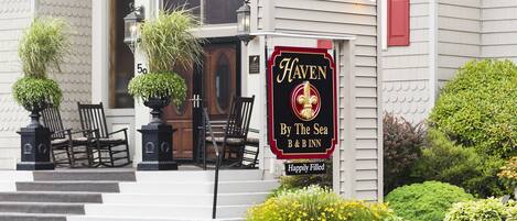 A hotel entrance with a sign reading "HAVEN By The Sea B&B INN" and a "Happily Filled" sign below it.