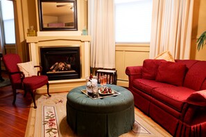 A living room with a fireplace, red furniture, and a tray with snacks. - Haven By The Sea B&B Inn (Wells)