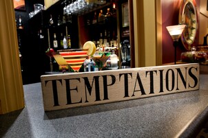 Una barra con un letrero que dice "TEMPTATIONS" y varios vasos de cóctel.
