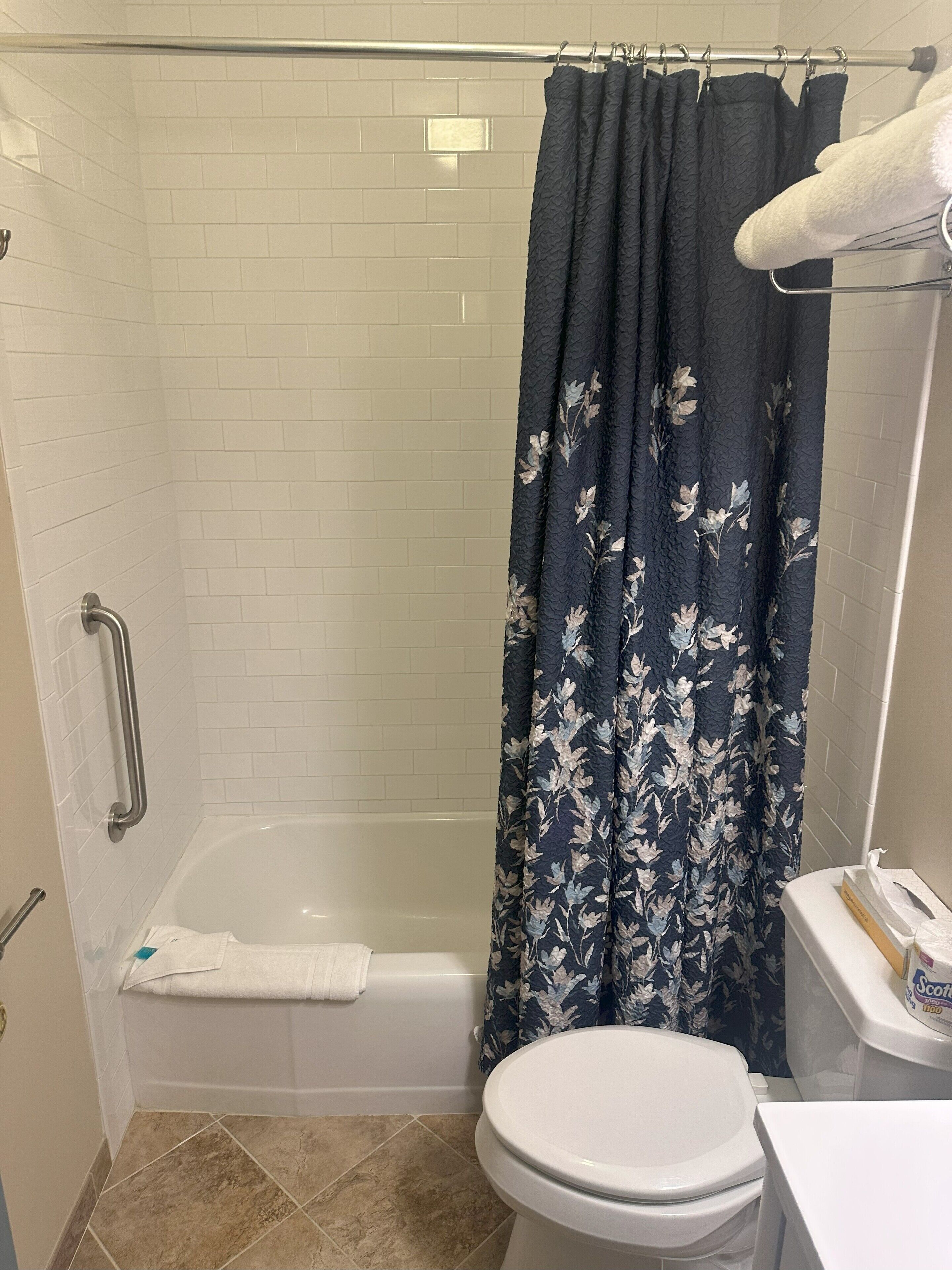 A bathroom with a shower, toilet, and a towel rack.