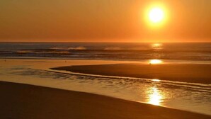 A beach at sunset with the sun low on the horizon, reflecting on the water. - Haven By The Sea B&B Inn (Wells)