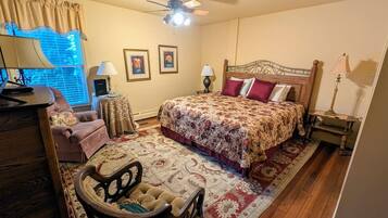 A bedroom with a bed, a chair, a desk, and a ceiling fan.