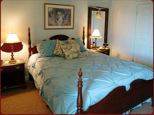 A bedroom with a bed, two nightstands, a mirror, and a painting on the wall. - Haven By The Sea B&B Inn (Wells)