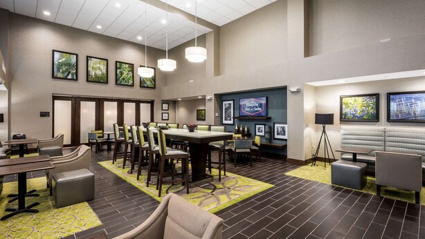 A hotel lobby with a large dining area, multiple seating options, and framed artwork on the walls.