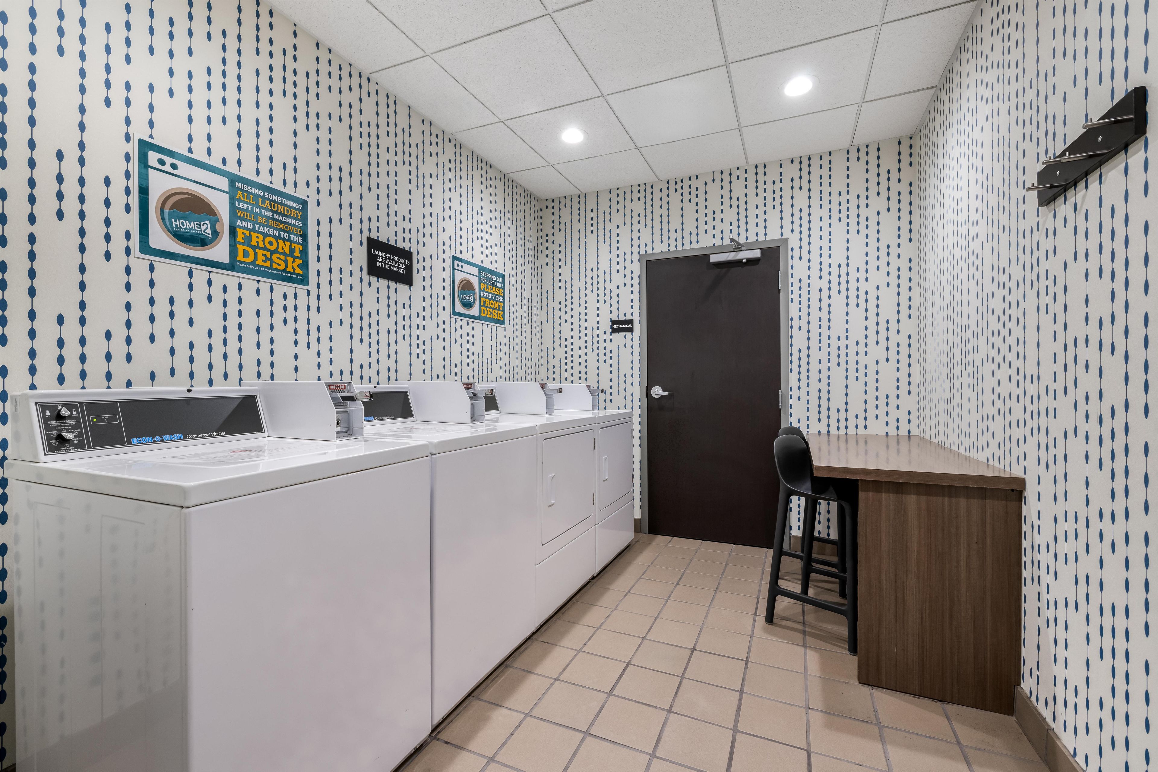 Zona de lavandería comercial con lavadoras, una recepción y una puerta.