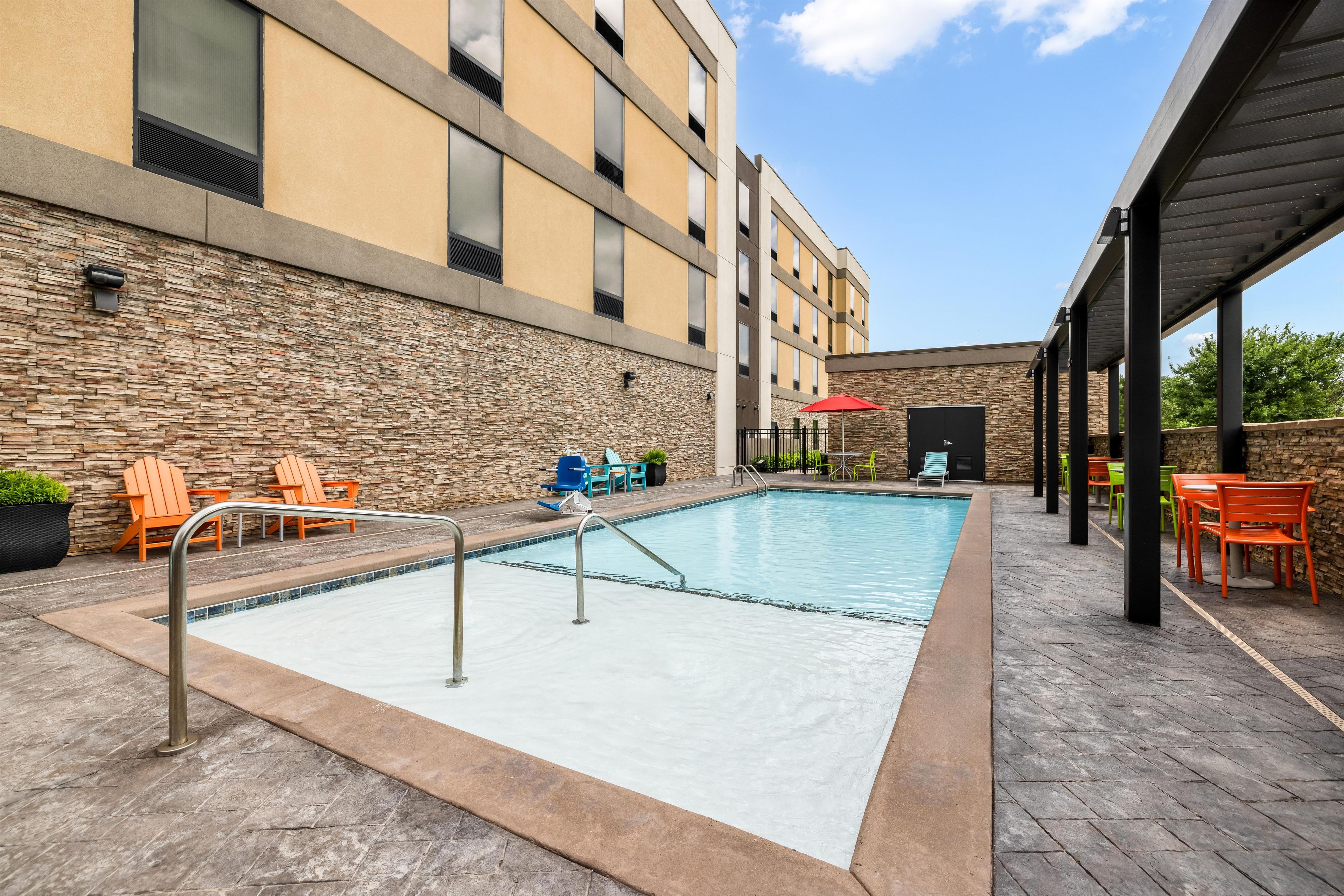 A swimming pool with a stone wall and outdoor seating area.
