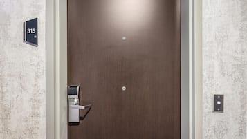 A hotel room door with a number plate, a doorbell, and a light switch.