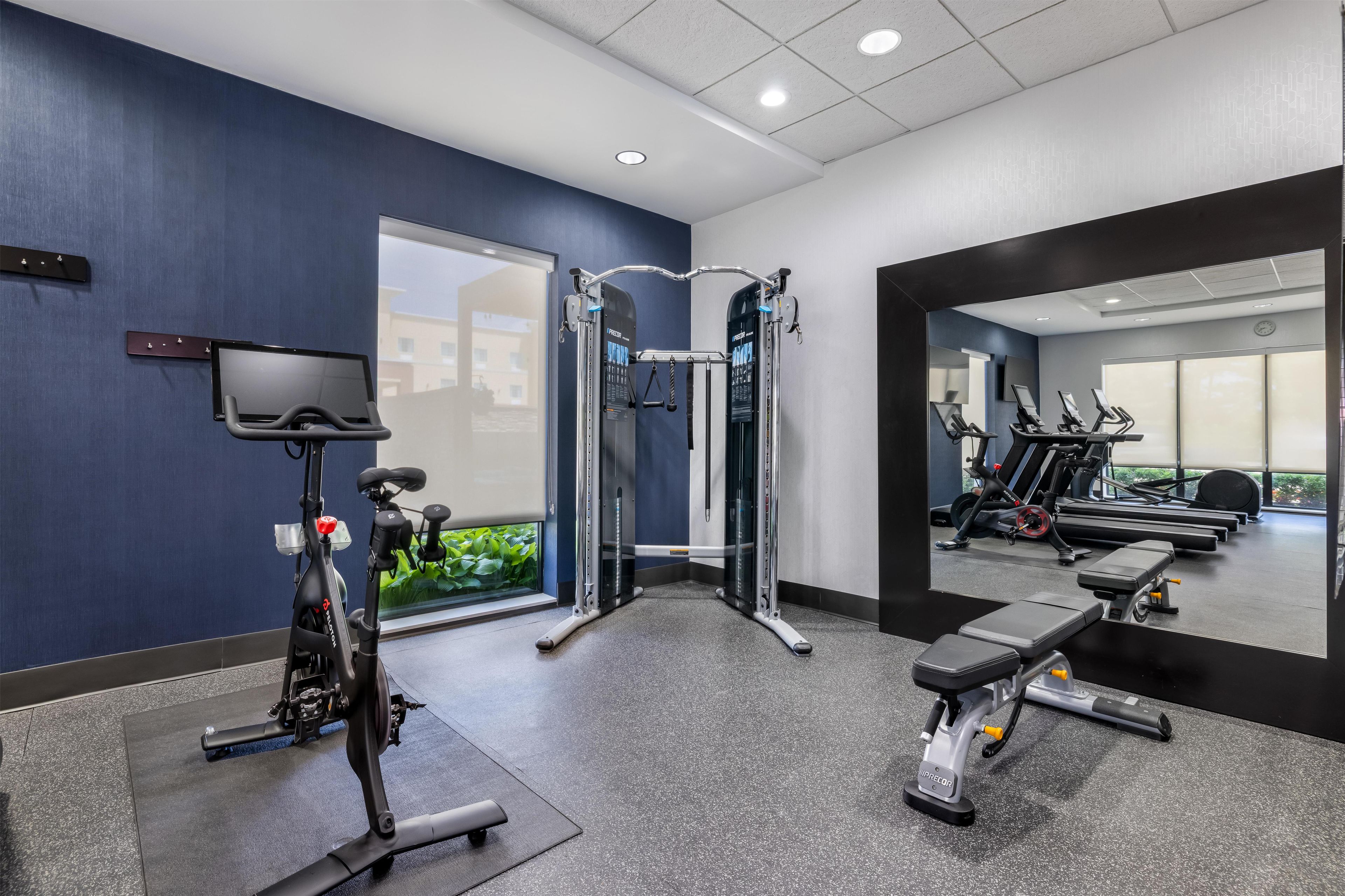 Un gimnasio con equipo de ejercicio, una televisión y una banca.
