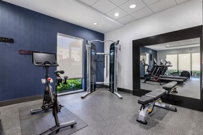Una sala de gimnàstica amb equip d'exercici, una televisió i una banca.